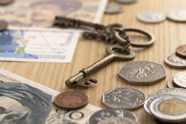 Eski anahtarlar, bozuk paralar ve banknotlar ahşap bir masanın üzerinde.