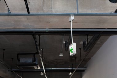 Endüstriyel tavandan sarkan yeşil acil çıkış işareti