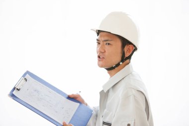 Üniformalı yakışıklı Japon inşaatçının portresi. İnşaat alanını pano ile inceliyor.