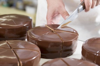 Şef çikolatalı keki bıçakla kesiyor.