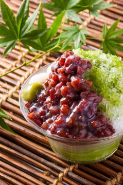 Arka planda haşlanmış azuki fasulyesi ve erikli Matcha buzu, yakın plan.