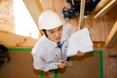 Ahşap binayı inceleyen Asyalı genç inşaat müfettişinin portresi.