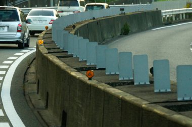 Virajlı otoyolda beton bariyerlerle giden arabalar görülüyor