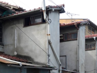 Gri duvarları ve fayanslı çatıları olan yıpranmış binalar.