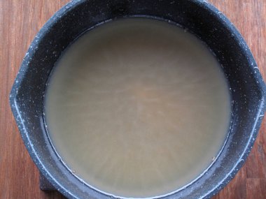 Yakın plan, açık kahverengi miso çorbası içeren tüten kaseyi gösteriyor.