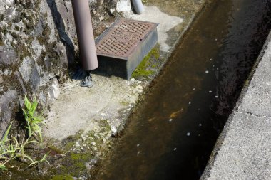 Dışarıdaki yıpranmış taş duvarın yanında beton drenaj kanalını daralt.