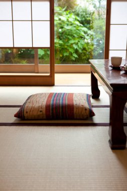 Tahta masanın yanında zabuton yastığı olan güneş yanığı tatami odası.