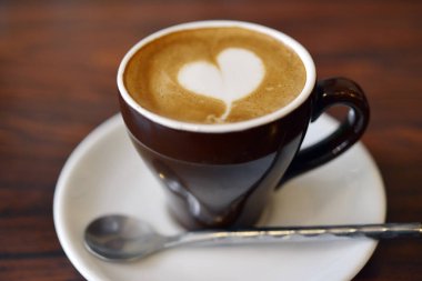 Sabahları ahşap bir masada bir fincan kapuçino..