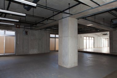 Gri duvarları ve boruları olan endüstriyel yapı.         