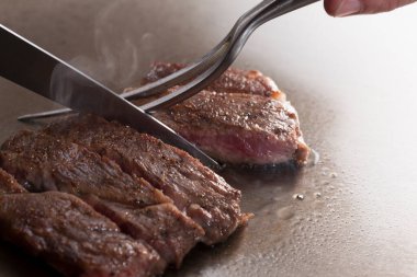 Çatal ve bıçakla kesilmiş taze bifteğin yakın plan görüntüsü                          