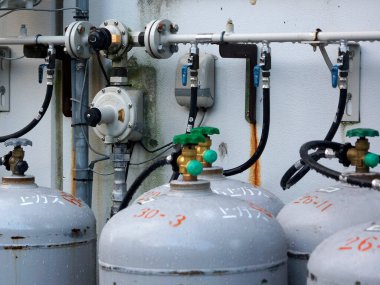 Endüstriyel gaz silindirleri duvara bağlı valflerle dolu.