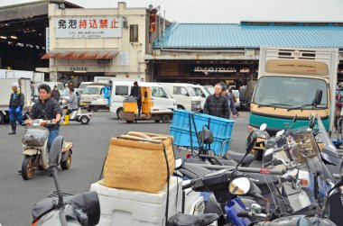 Mobiletlerin, kamyonların, insanların malları taşıdığı açık hava piyasası manzarası