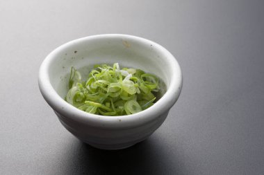 Beyaz seramik kasede dilimlenmiş yeşil soğan.