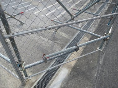 Metal çitler boş şehir kaldırımlarında gölgeler bırakıyor.