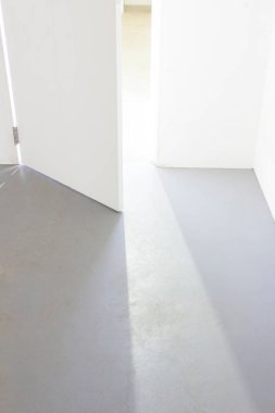 Beton zemini ve açık kapısı olan beyaz ve gri boş bir oda.