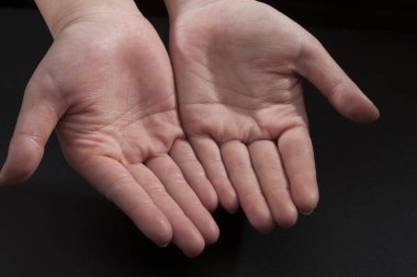 Avuç içlerini siyah arkaplanda gösteren açık eller