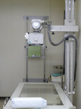 Modern X-ray cihazı temiz tıbbi muayene odasında duruyor.