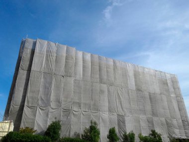 Mavi gökyüzüne karşı koruyucu kumaşla kaplı bina