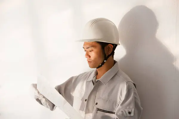 portrait of handsome young Japanese builder in uniform at construction site
