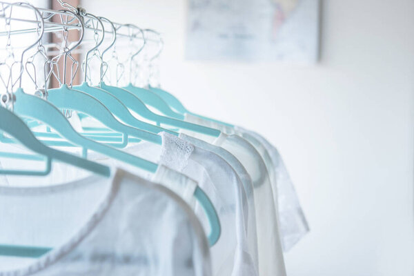 Висячая одежда на синих вешалках в светлой комнате