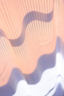 Güneş ışınları penceredeki şeffaf perdeyi aydınlatıyor