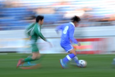 Genç Japon erkekler stadyumda futbol oynuyor, spor geçmişi bulanık insanlarla dolu. 