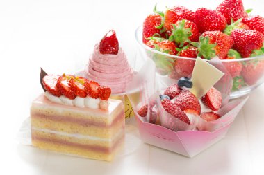 Masada meyve ve krema bulunan çeşitli tatlılar.