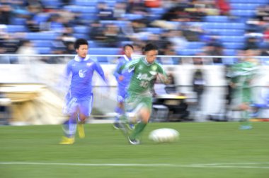 Genç Japon erkekler stadyumda futbol oynuyor, spor geçmişi bulanık insanlarla dolu. 