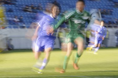 Genç Japon erkekler stadyumda futbol oynuyor, spor geçmişi bulanık insanlarla dolu. 