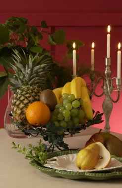 Bir tabak meyve ve şamdanlı bir masa.