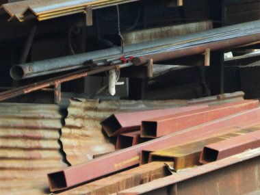 Yıpranmış ahşap yapıya dayanan paslı metal borular.