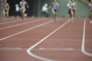 Genç Japon kadınlar stadyumda koşup zıplıyorlar.