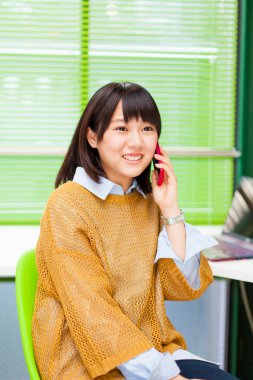 Ofisinde akıllı telefonu olan güzel Asyalı bir kadının portresi.