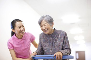 Gülümseyen bakıcı yaşlı kadına Walker 'la yardım ediyor.