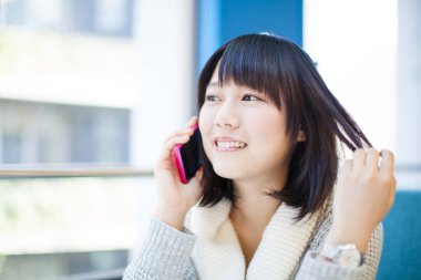 Akıllı telefonlu güzel Asyalı bir kadının yakın plan portresi.