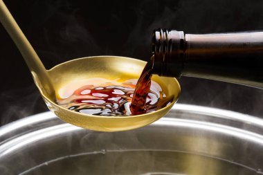 Metal bir kaseden kaşığa bal döküyorum.