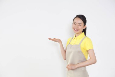 Önlüklü gülümseyen kadın boş duvara işaret ediyor.