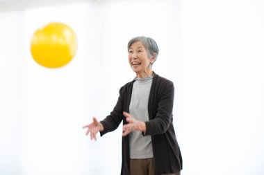 Üst düzey Japon kadın beyaz arka planda topla oynuyor.