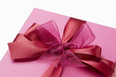 Kırmızı kurdeleli pembe bir hediye kutusu.