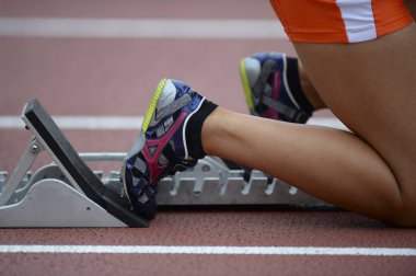 Bayan koşucu ayakkabısını koşu yarışına bağlıyor.