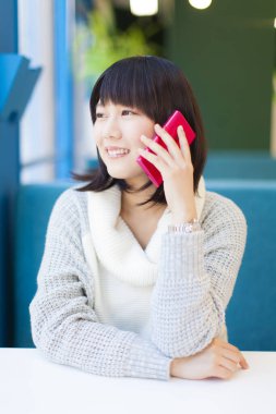 Akıllı telefonlu güzel Asyalı bir kadının yakın plan portresi.