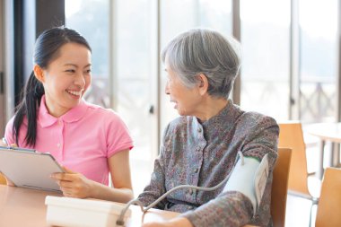 Muayene sırasında yaşlı kadına yardım eden hemşire.