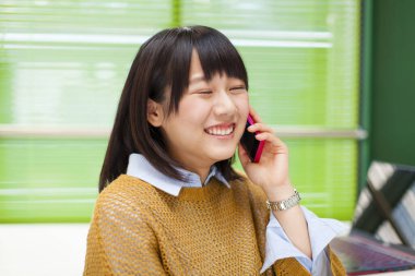 Ofisinde akıllı telefonu olan güzel Asyalı bir kadının portresi.