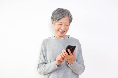 Beyaz bir geçmişi olan Asyalı bir kadın telefona gülümsüyor.