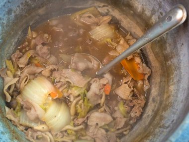 Sebzeli tavuk suyu ve tencerede kepçe.