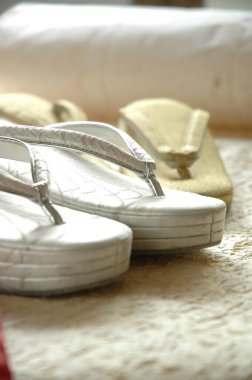 Gümüş ve bej renkli sandaletler halıda