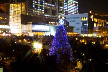 Güzel dekore edilmiş Noel ağacı ve gece şehrindeki insanlar..            