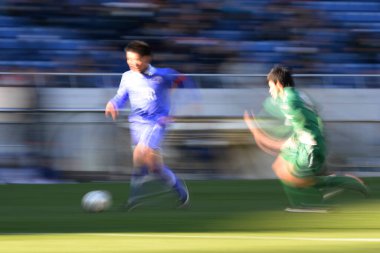 Genç Japon erkekler stadyumda futbol oynuyor, spor geçmişi bulanık insanlarla dolu. 