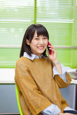 Ofisinde akıllı telefonu olan güzel Asyalı bir kadının portresi.