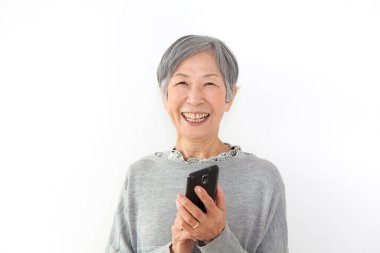 Beyaz bir geçmişi olan Asyalı bir kadın telefona gülümsüyor.